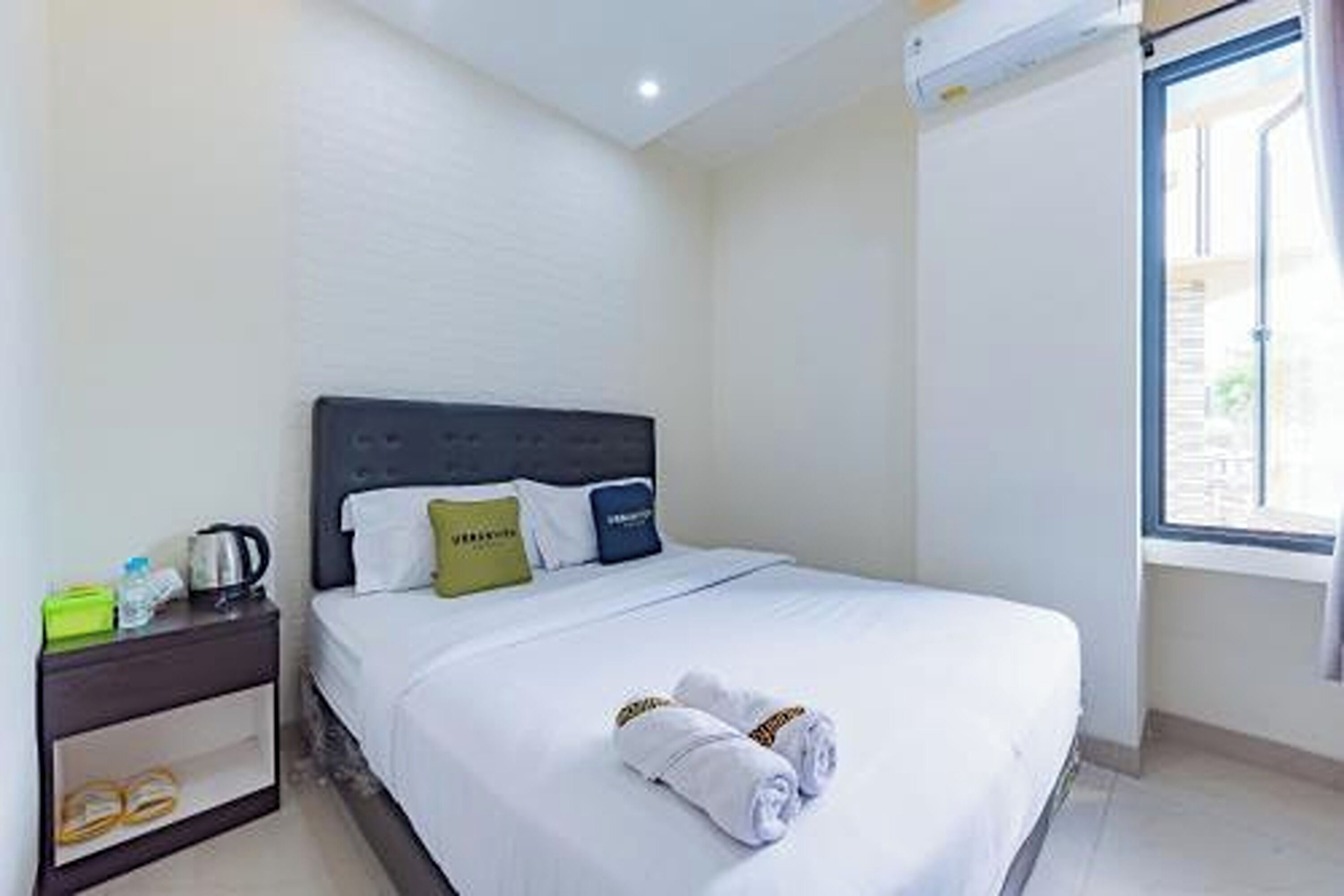 A hotel room with a bed, a nightstand, a window, and a view of the outside.