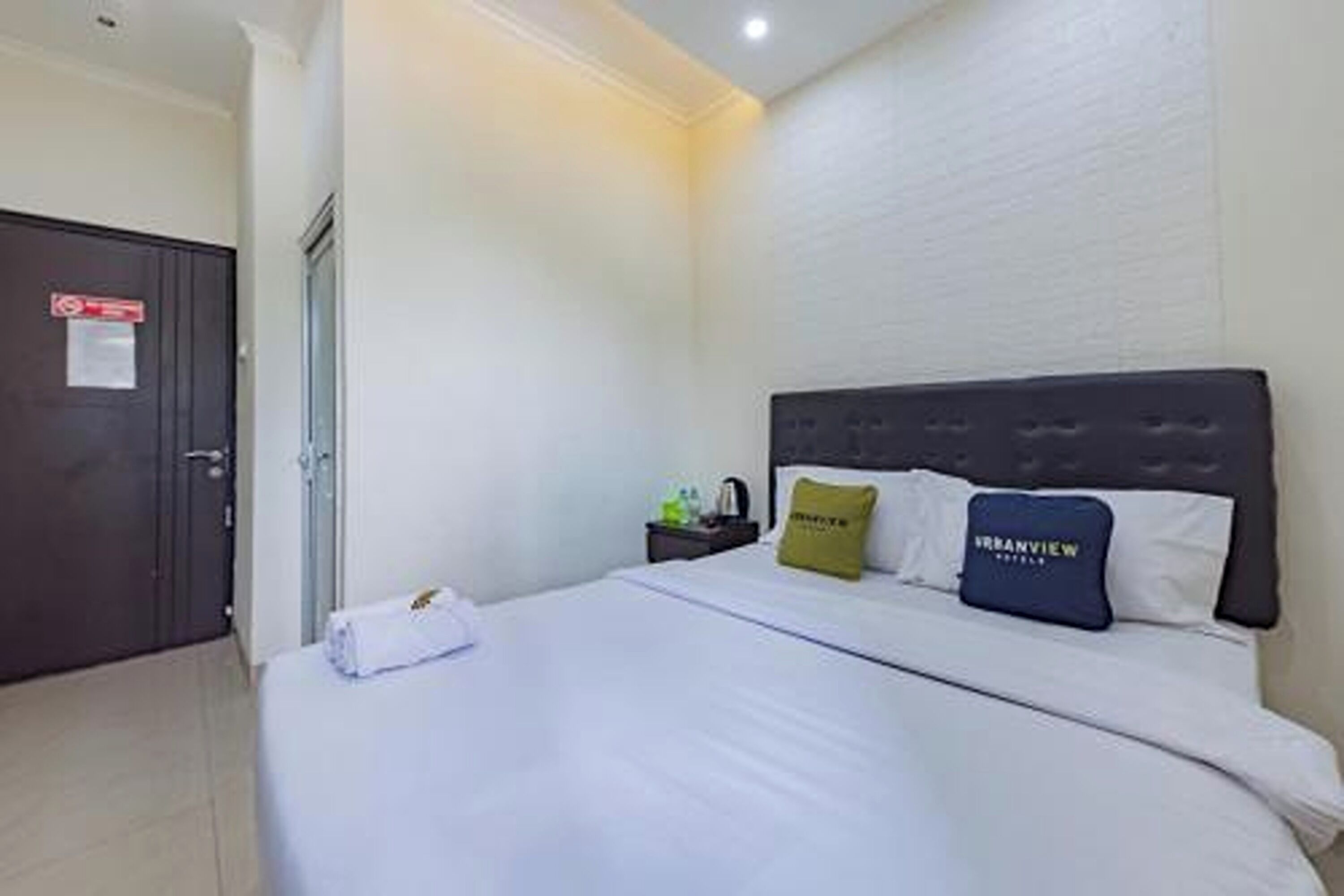 A hotel room with a bed, a nightstand, and a door.