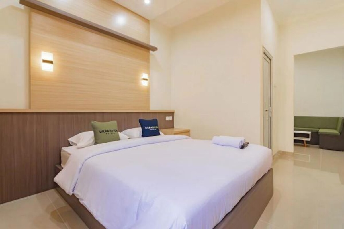 Een moderne hotelkamer met een groot bed, een houten hoofdbord en een klein nachtkastje.
