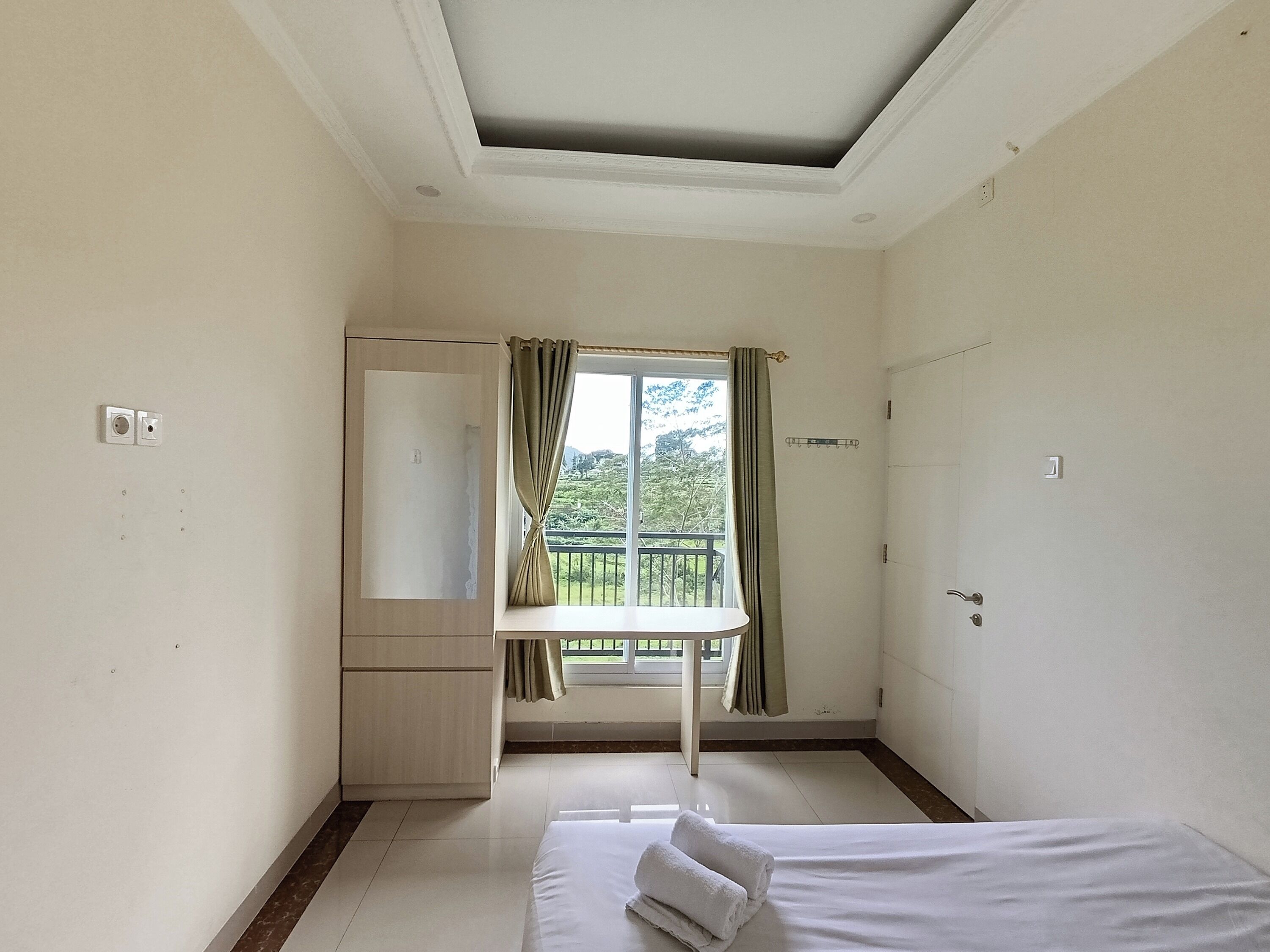 Une chambre à coucher avec un lit, un bureau et une fenêtre avec des rideaux.