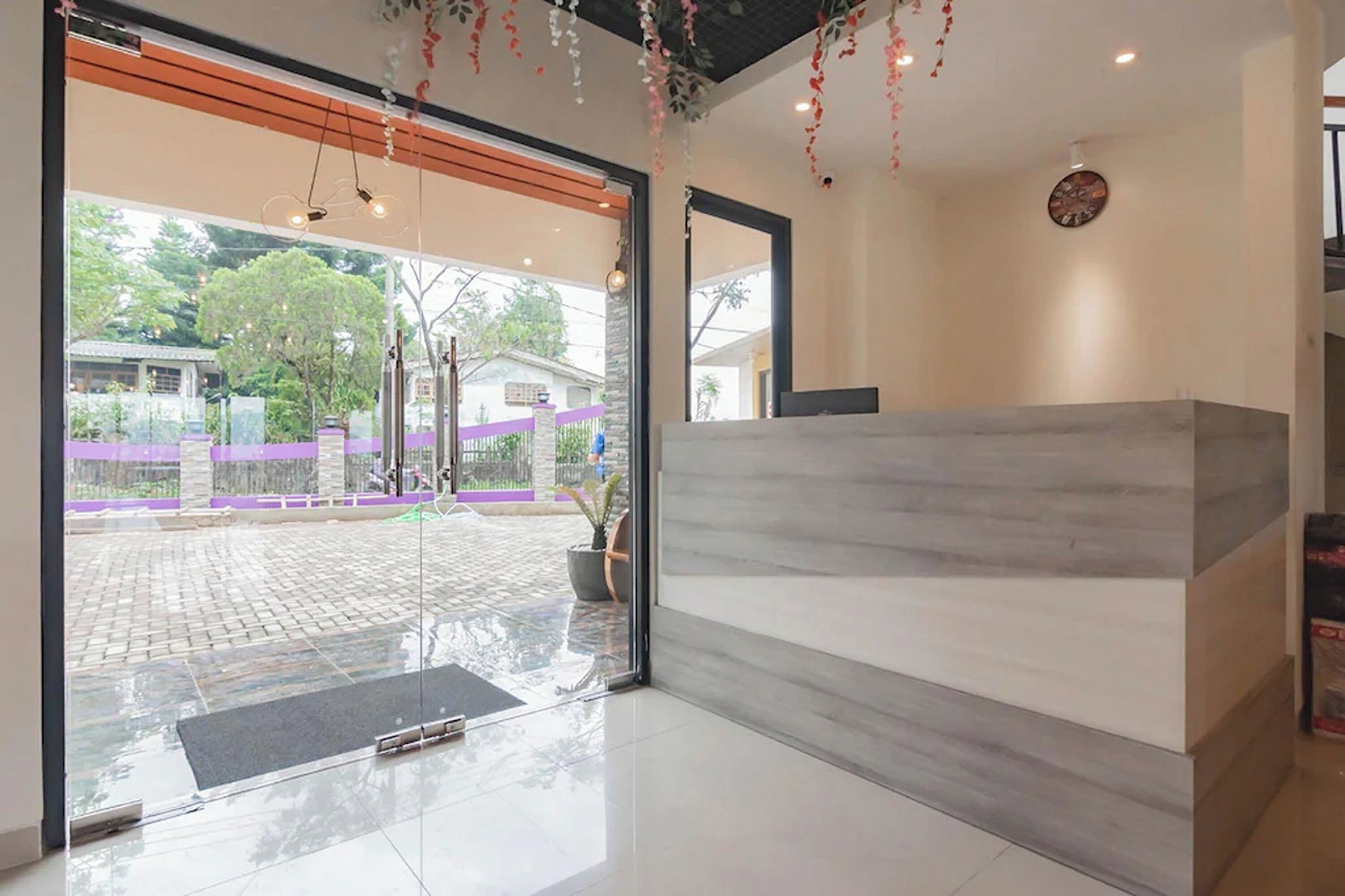 A reception area with a marble counter, a large glass door leading outside, and a clock on the wall.