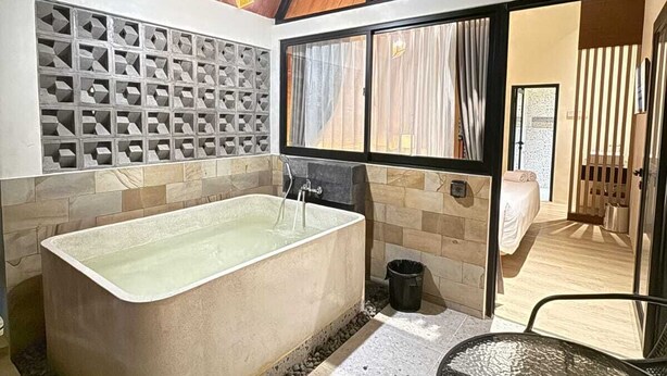 Een moderne badkamer met een vrijstaand bad, een douchecabine van glas en een groot raam voor natuurlijk licht.