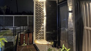 Een moderne buitenruimte met een houten terras, potplanten en een glazen deur naar een gebouw.