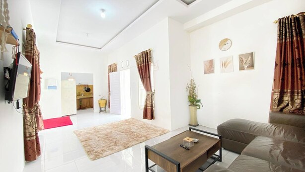 A modern living room with a sofa, coffee table, and a kitchen in the background. - Villa Palacios Syari'Ah Bukittinggi (Bukittinggi)