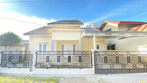 A two-story house with a tiled roof, a balcony, and a gated entrance. - Villa Palacios Syari'Ah Bukittinggi (Bukittinggi)