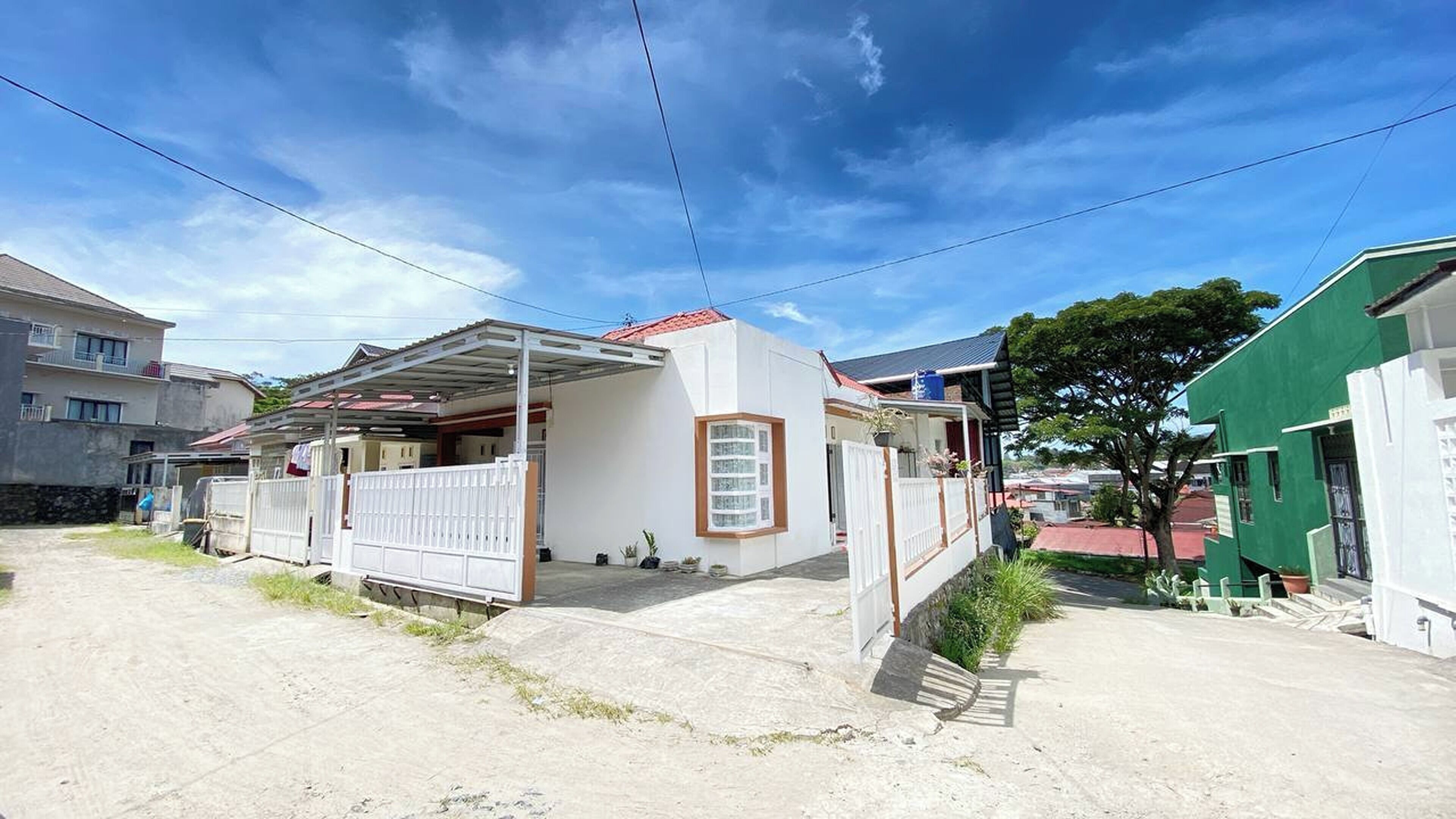 A residential house with a covered porch, a fenced yard, and a clear sky.
