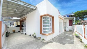 A modern house with a covered patio, a large window with multiple panes, and a small garden area with potted plants. - Villa Palacios Syari'Ah Bukittinggi (Bukittinggi)