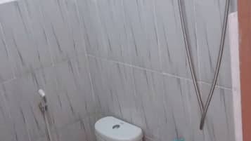 A small bathroom with a toilet, a shower, and a wall-mounted faucet.
