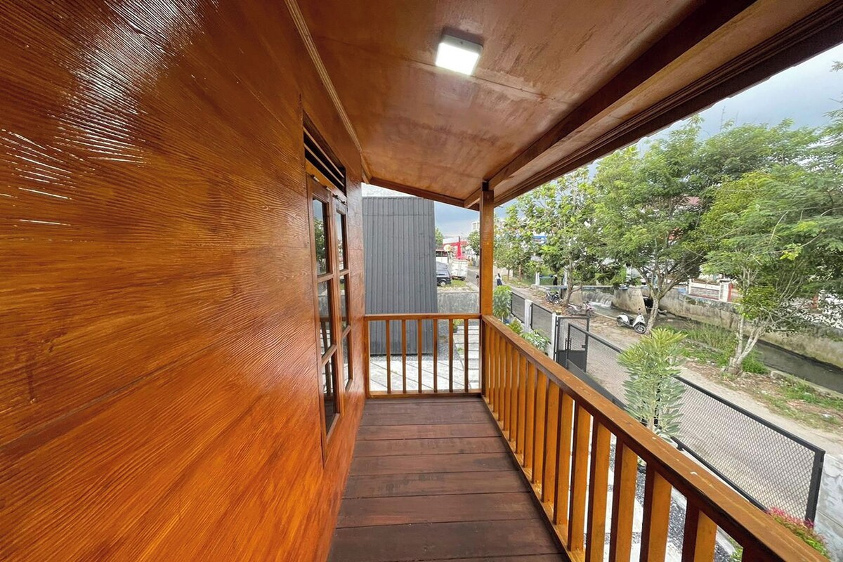 A wooden balcony with a view of a river and greenery.