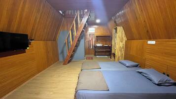 Een chalet met houten wanden, een trap en drie bedden met blauw beddengoed.