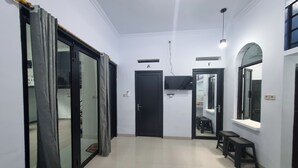 Un corridoio con una porta nera con l'indicazione 'A', una porta nera con l'indicazione 'F' e uno specchio appeso al muro.