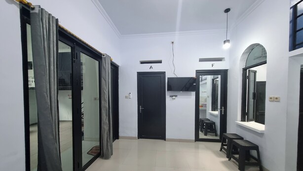 A hallway with a black door labeled 'A', a black door labeled 'F', and a mirror on the wall.