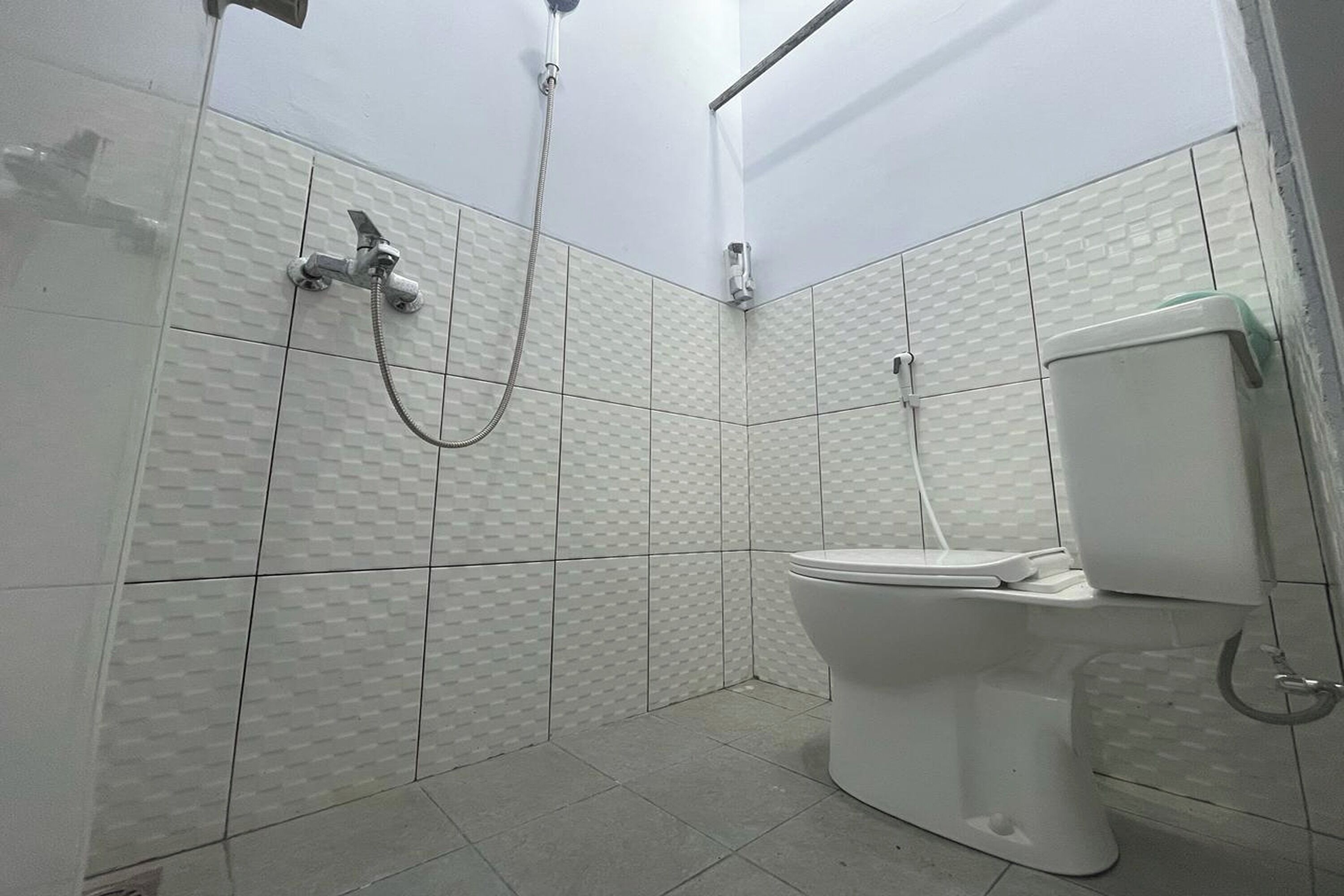 Une salle de bain avec des toilettes, une douche et un mur carrelé.