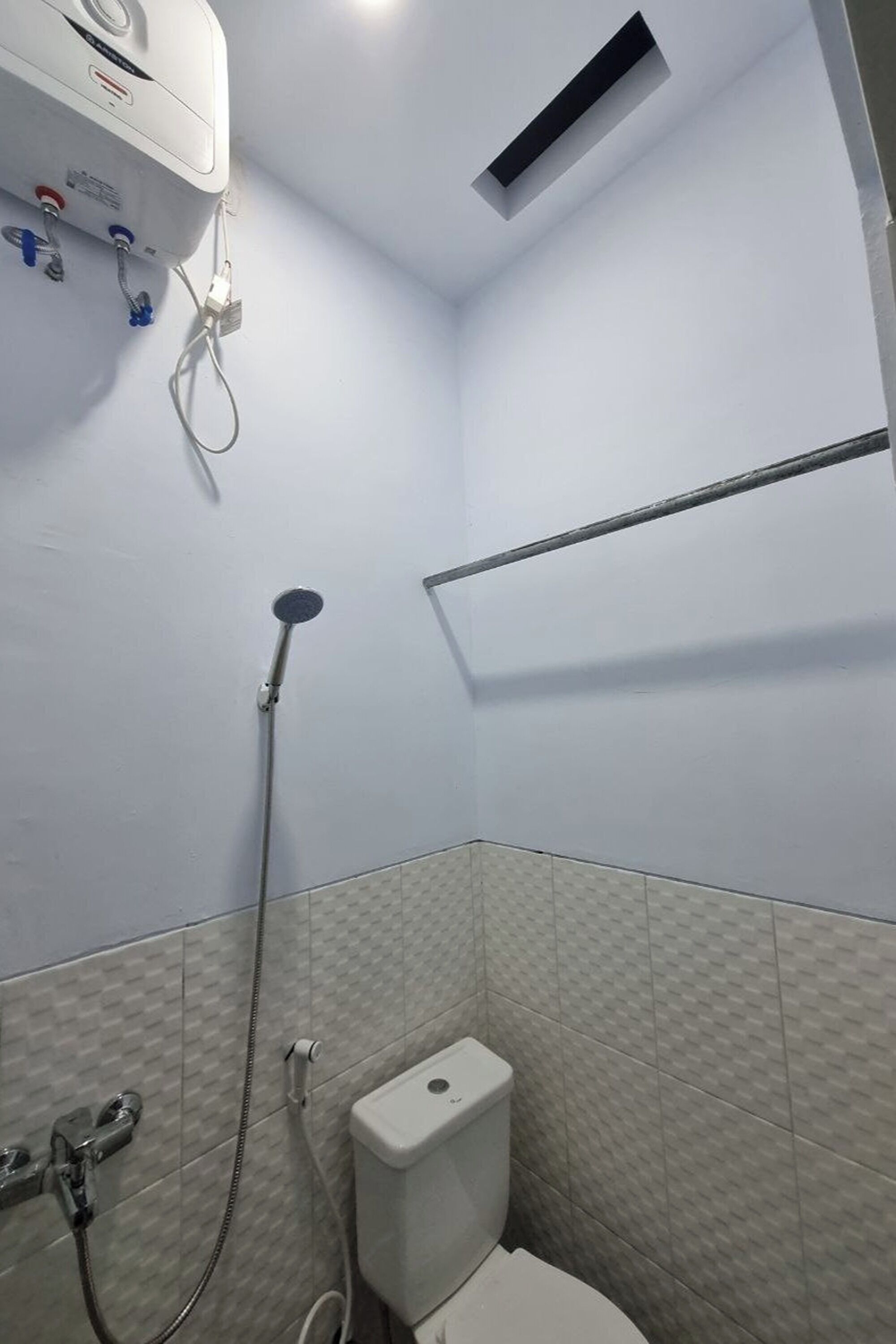 Une petite salle de bain comprenant des toilettes, une douche et un radiateur fixé au mur.