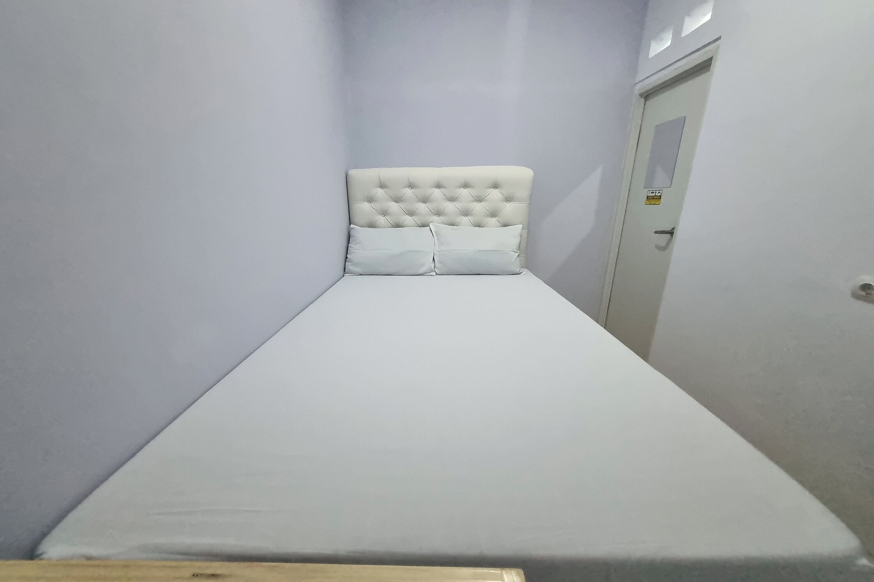 Ein schmaler, Einzelzimmer mit einer geblatteten Kopfteil und zwei Kissen.