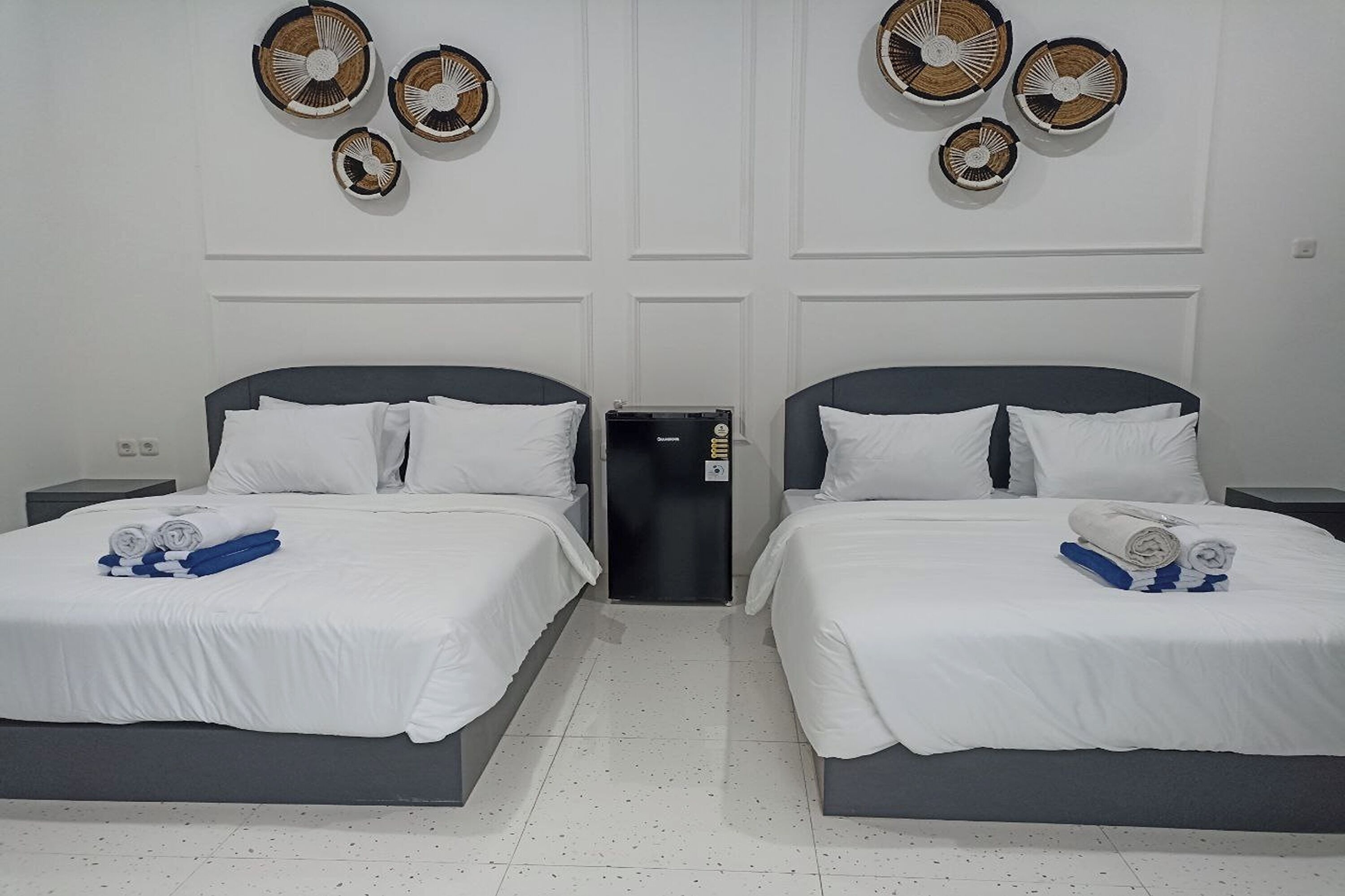 A hotel room with two beds, white bedding, and a small trash bin.