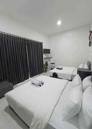 A hotel room with two beds, a desk, a TV, and a plant. - House Of Marvilla (Depok)