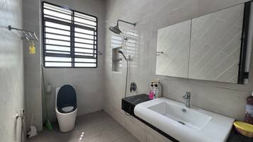 A modern bathroom with a toilet, bidet, sink, and shower.