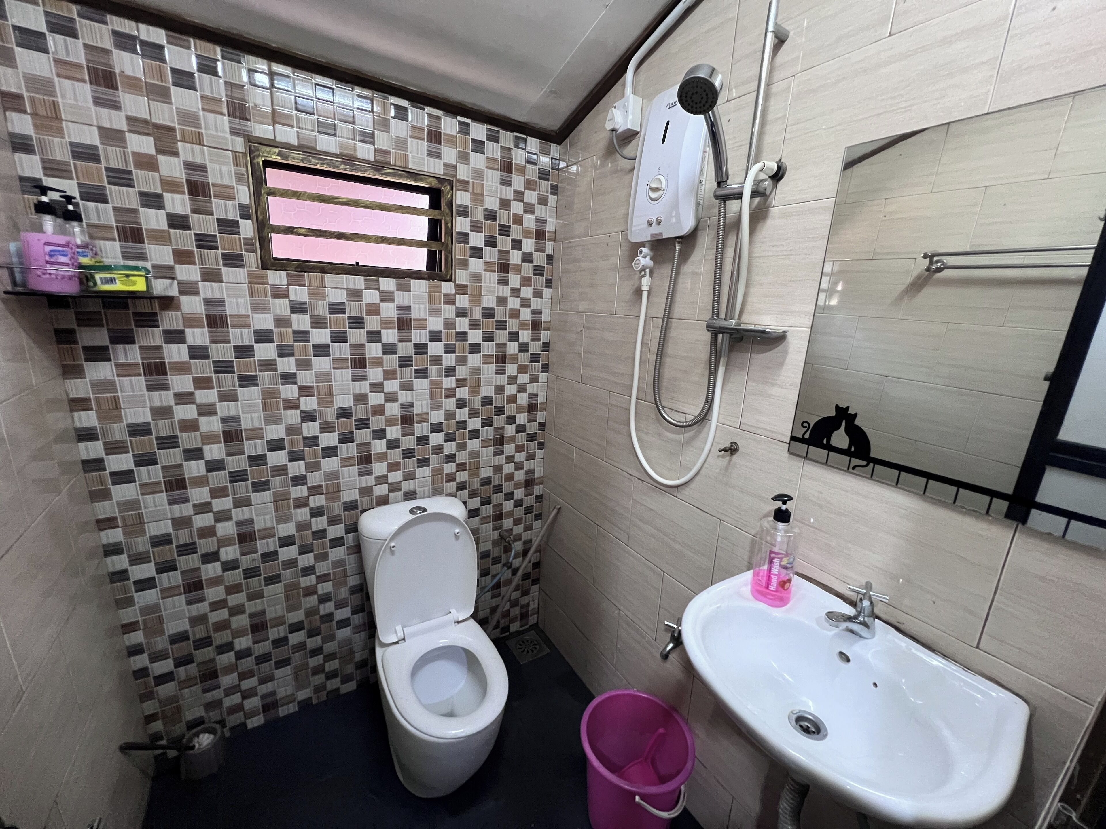 A small bathroom with a tiled floor, a toilet, a sink, and a shower.