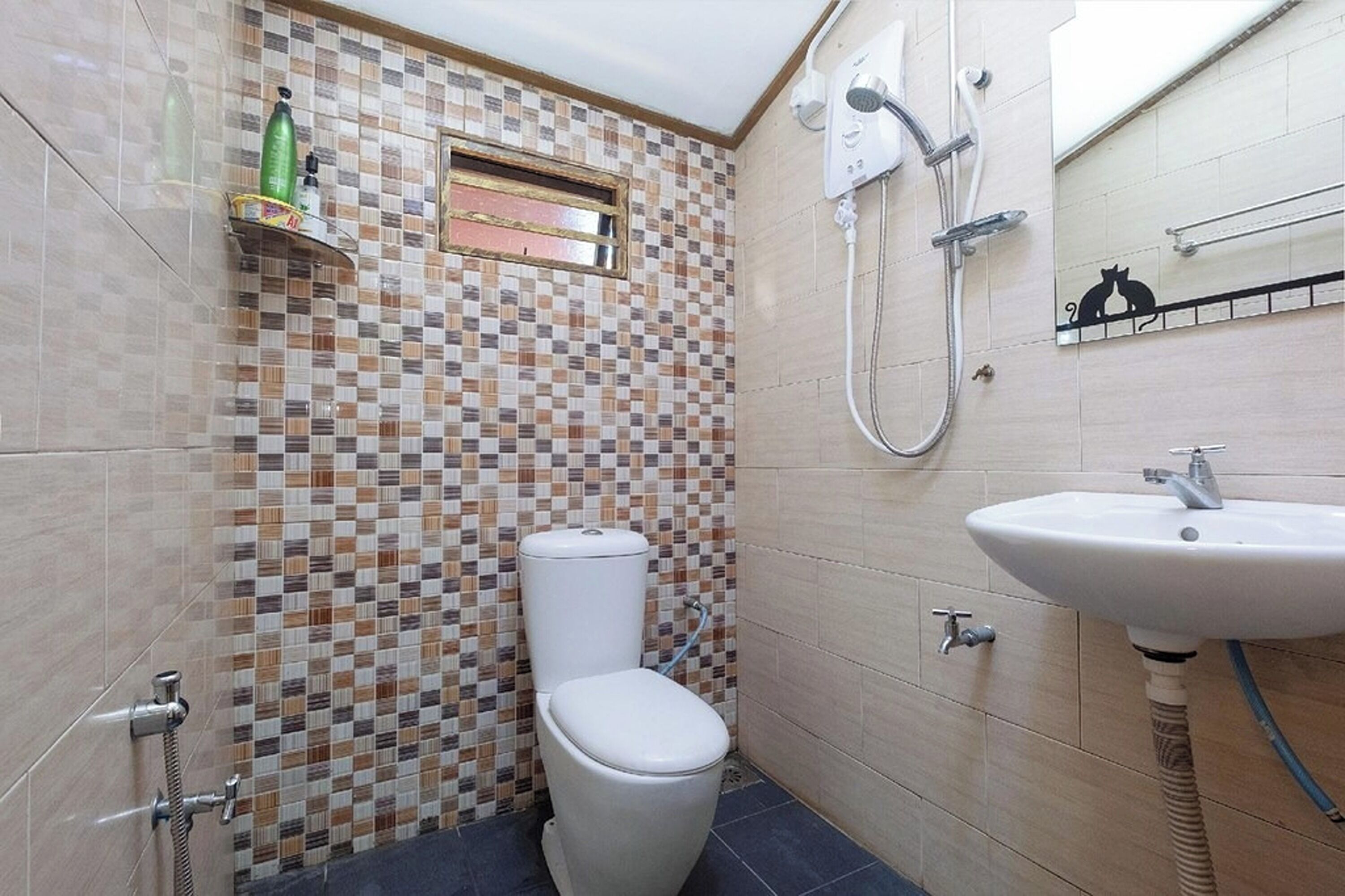 Une salle de bain avec un mur recouvert d’une mosaïque, des toilettes, un lavabo et une douche.