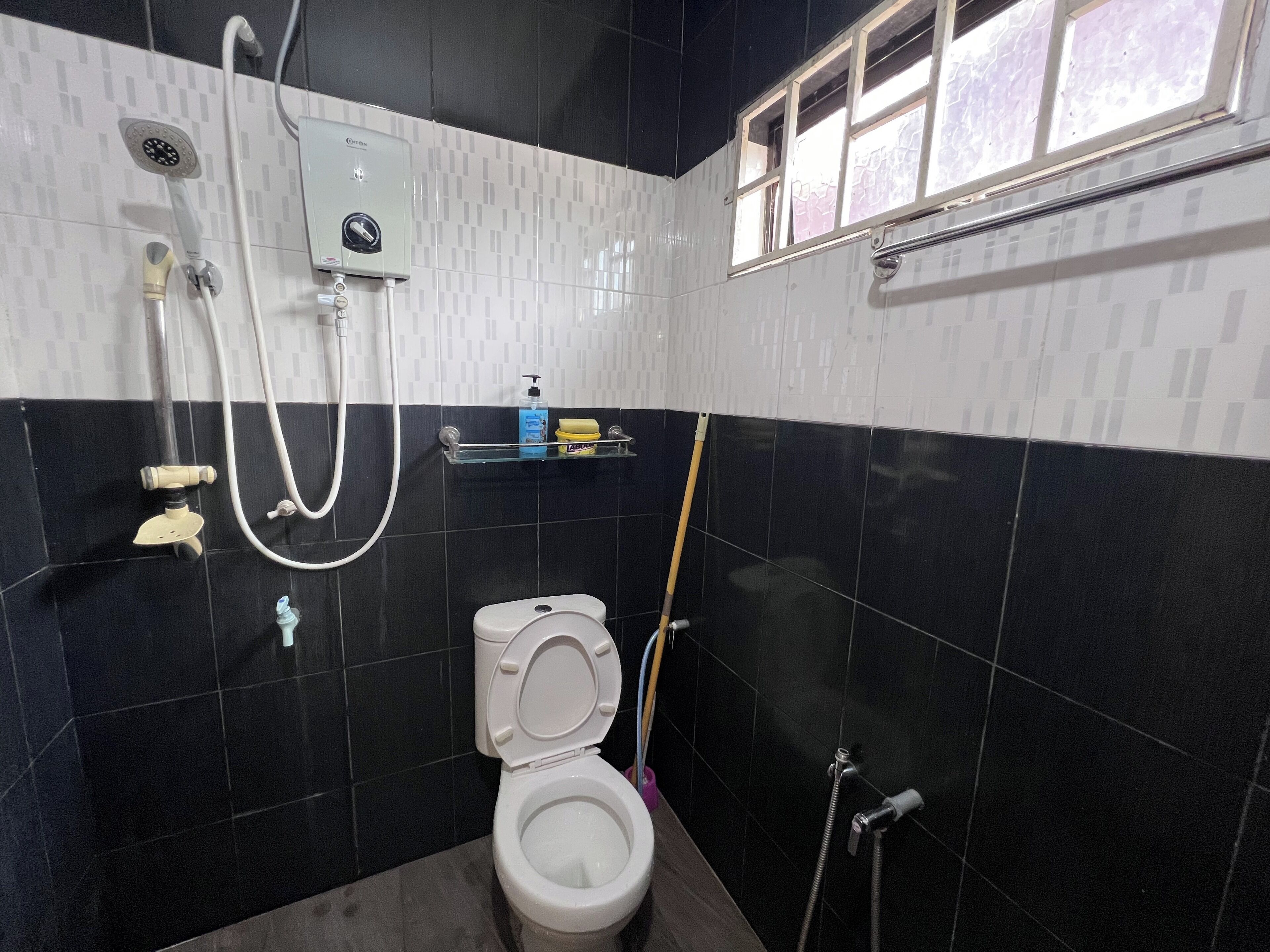 A bathroom with a toilet, a shower, and a window.