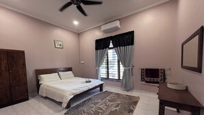 A bedroom with a bed, a ceiling fan, an air conditioner, a window with curtains, a bedside table, and a wall-mounted mirror. - Nurbayu Villa (3 and 4 bedroom Villa) Kemaman (Chukai)