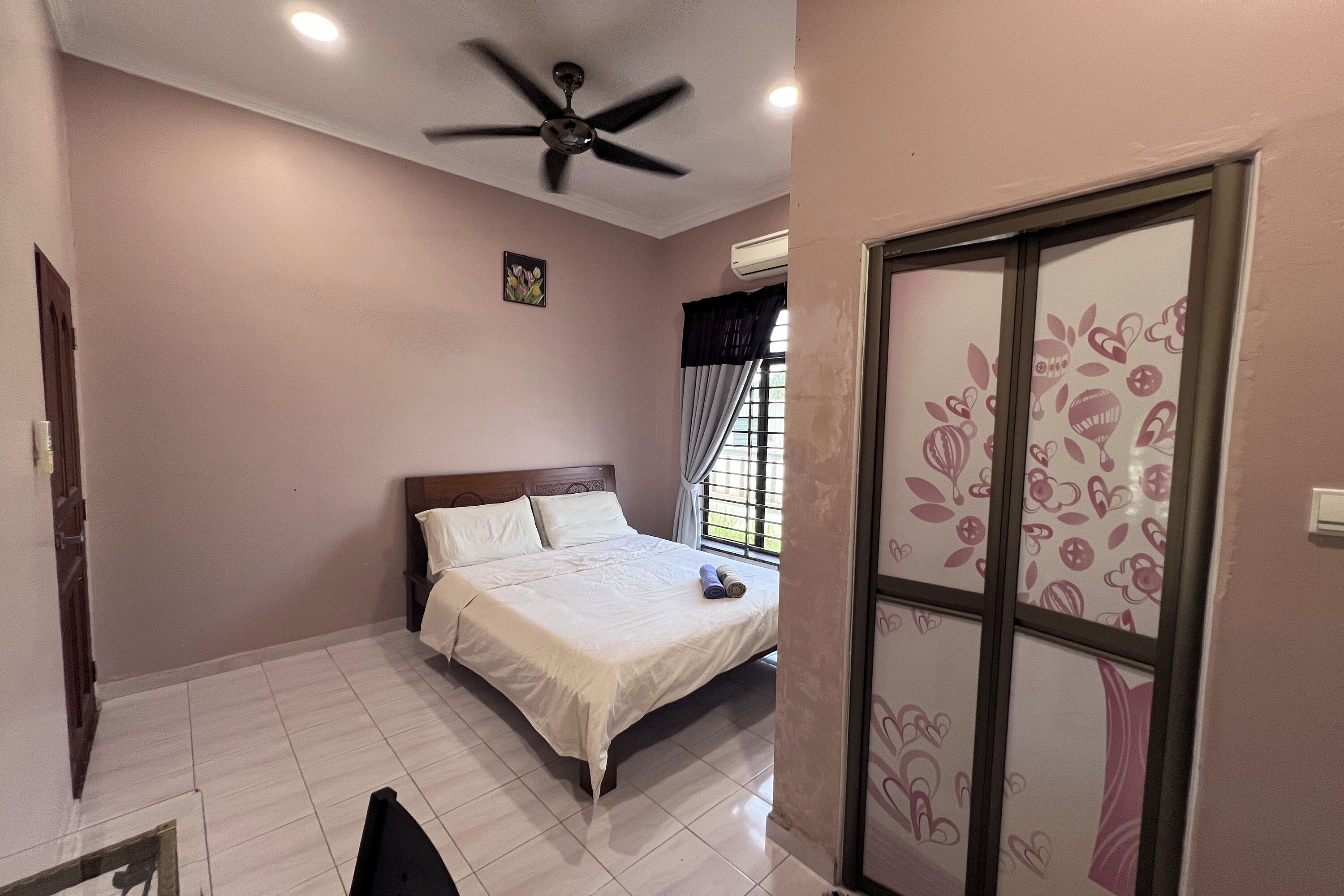 A bedroom with a bed, ceiling fan, and a window with curtains.