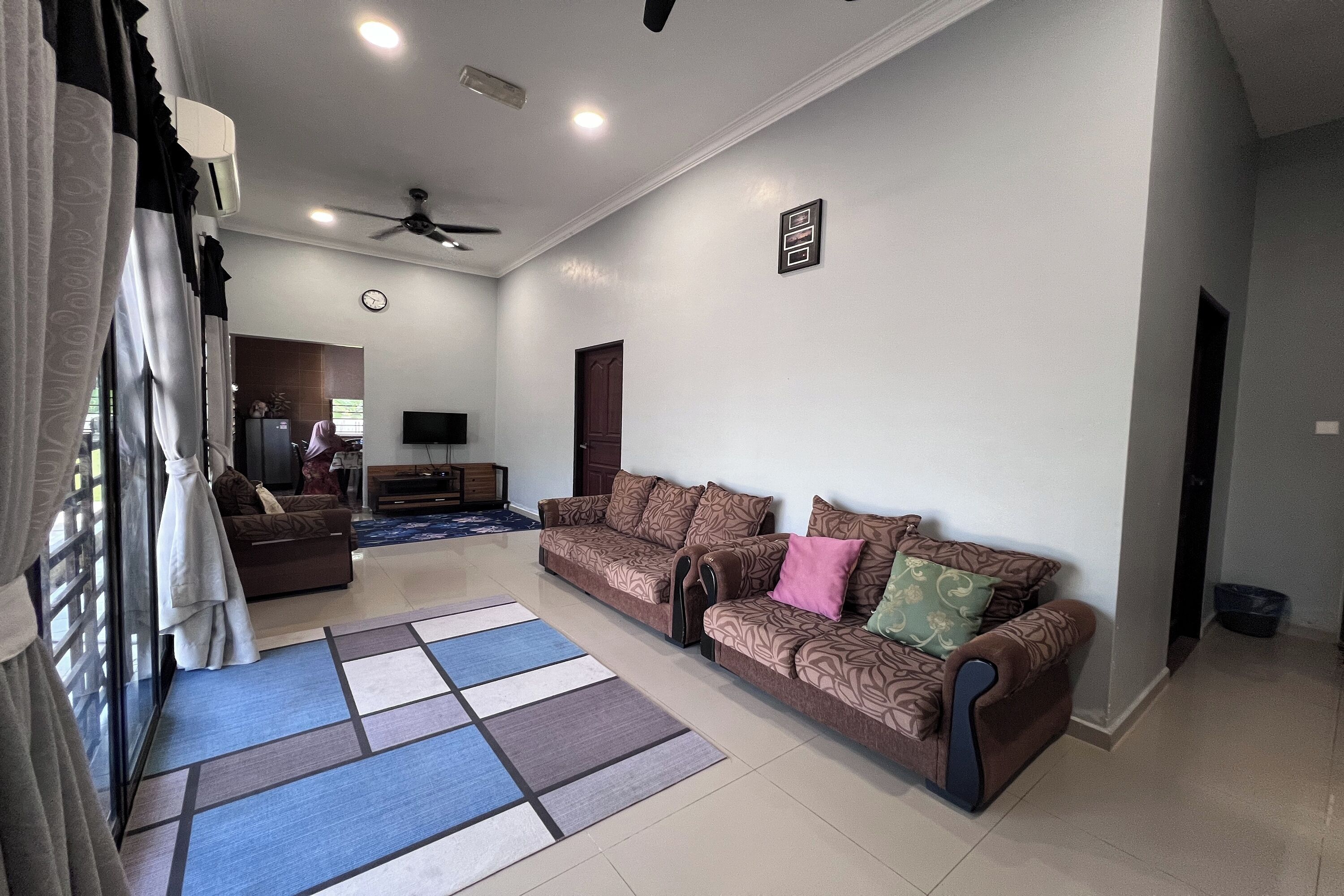 A living room with a sofa, a coffee table, a TV, and a ceiling fan.