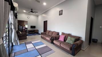 A living room with a sofa, a coffee table, a TV, and a ceiling fan.