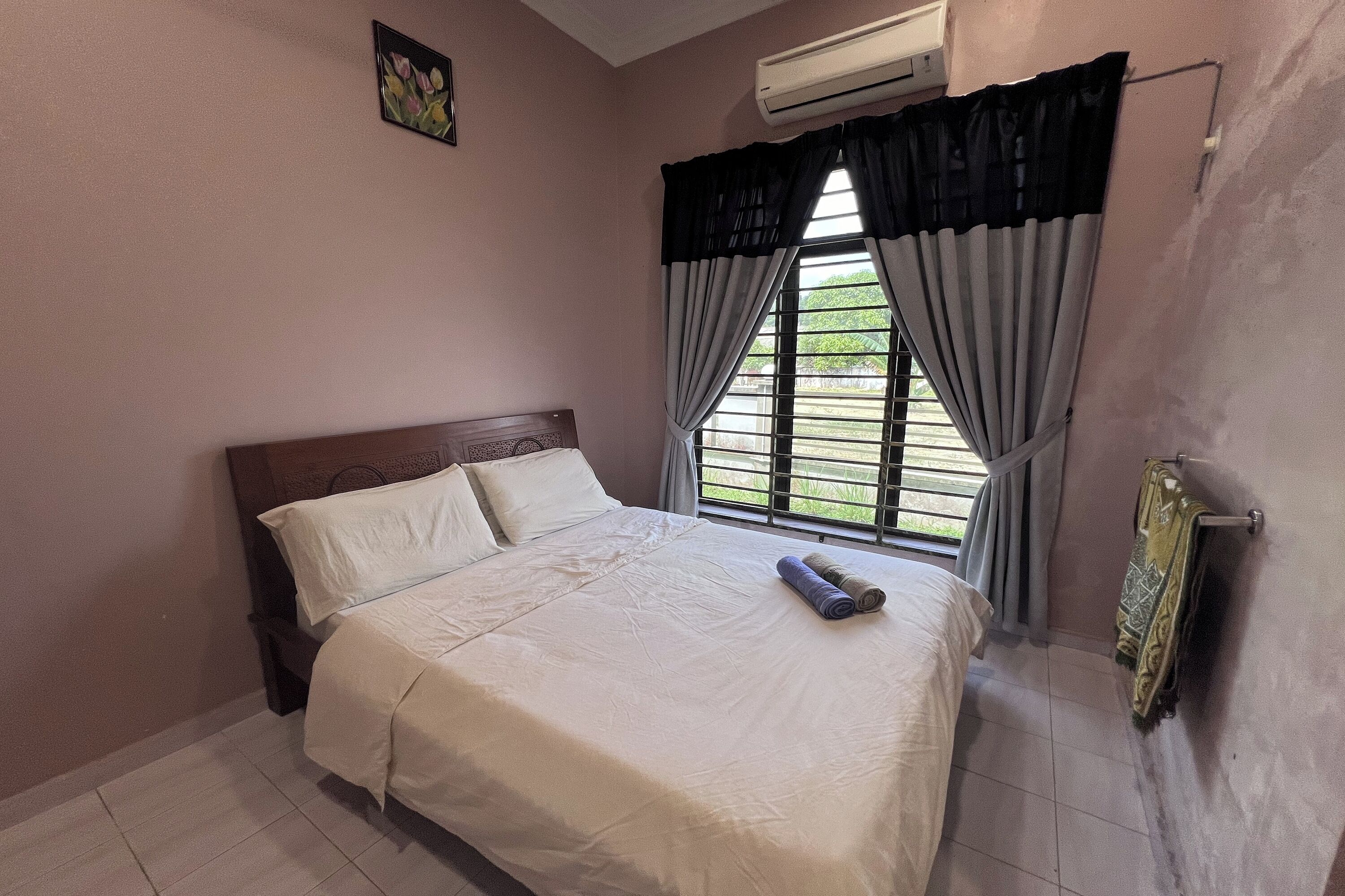 A bedroom with a bed, a window with curtains, an air conditioner, and a radiator.