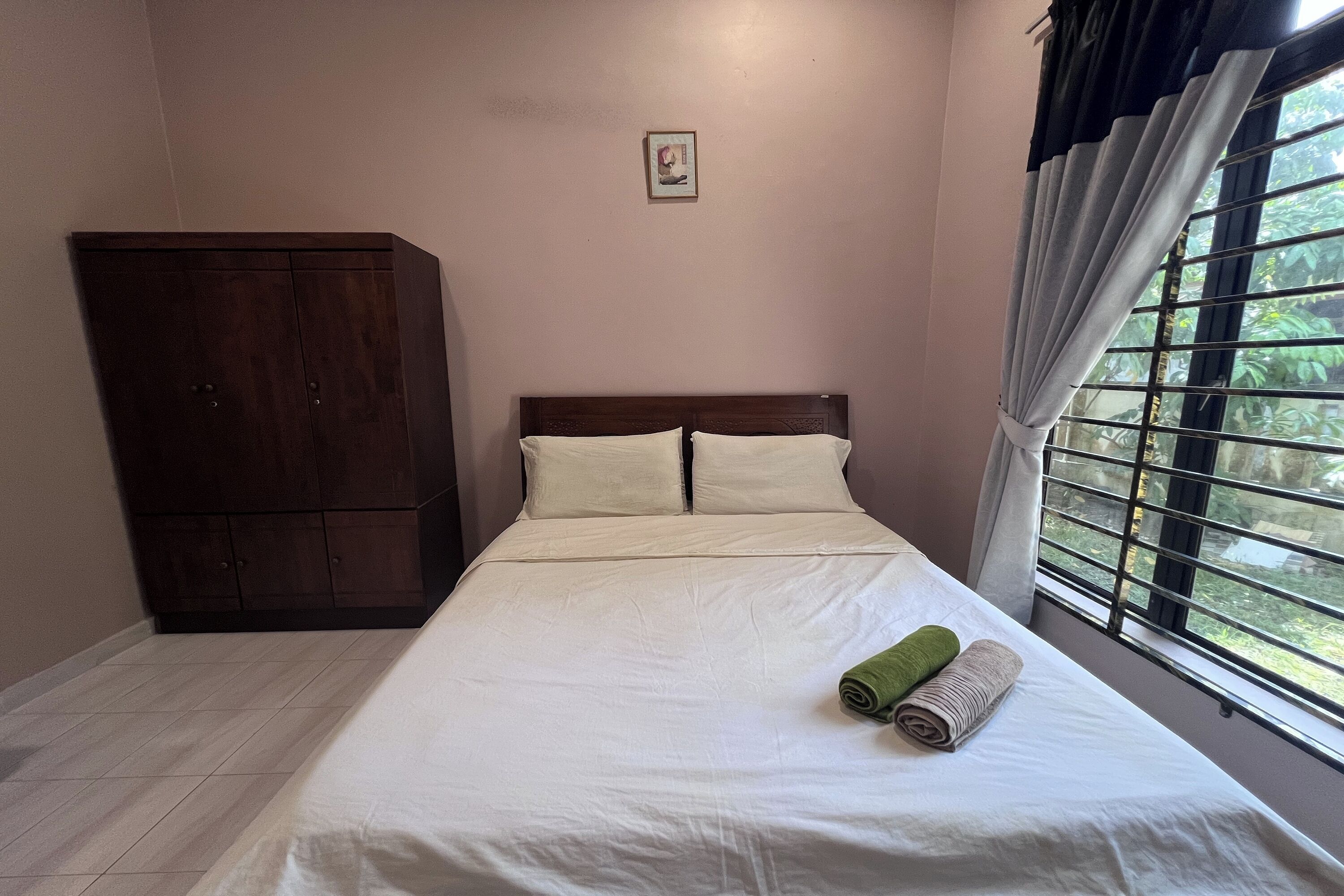 A bedroom with a bed, a wardrobe, and a window with curtains.