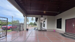 A covered outdoor area with tiled flooring, a metal gate, and a building entrance. - Nurbayu Villa (3 and 4 bedroom Villa) Kemaman (Chukai)