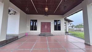 A covered outdoor area with a tiled floor, a central door, and a ceiling fan. - Nurbayu Villa (3 and 4 bedroom Villa) Kemaman (Chukai)