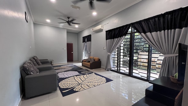 A spacious living room with a large window, ceiling fans, and a flat-screen TV. - Nurbayu Villa (3 and 4 bedroom Villa) Kemaman (Chukai)