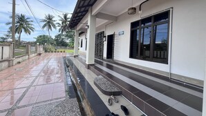A covered outdoor area with a tiled floor, a small seating area, and a large window. - Nurbayu Villa (3 and 4 bedroom Villa) Kemaman (Chukai)