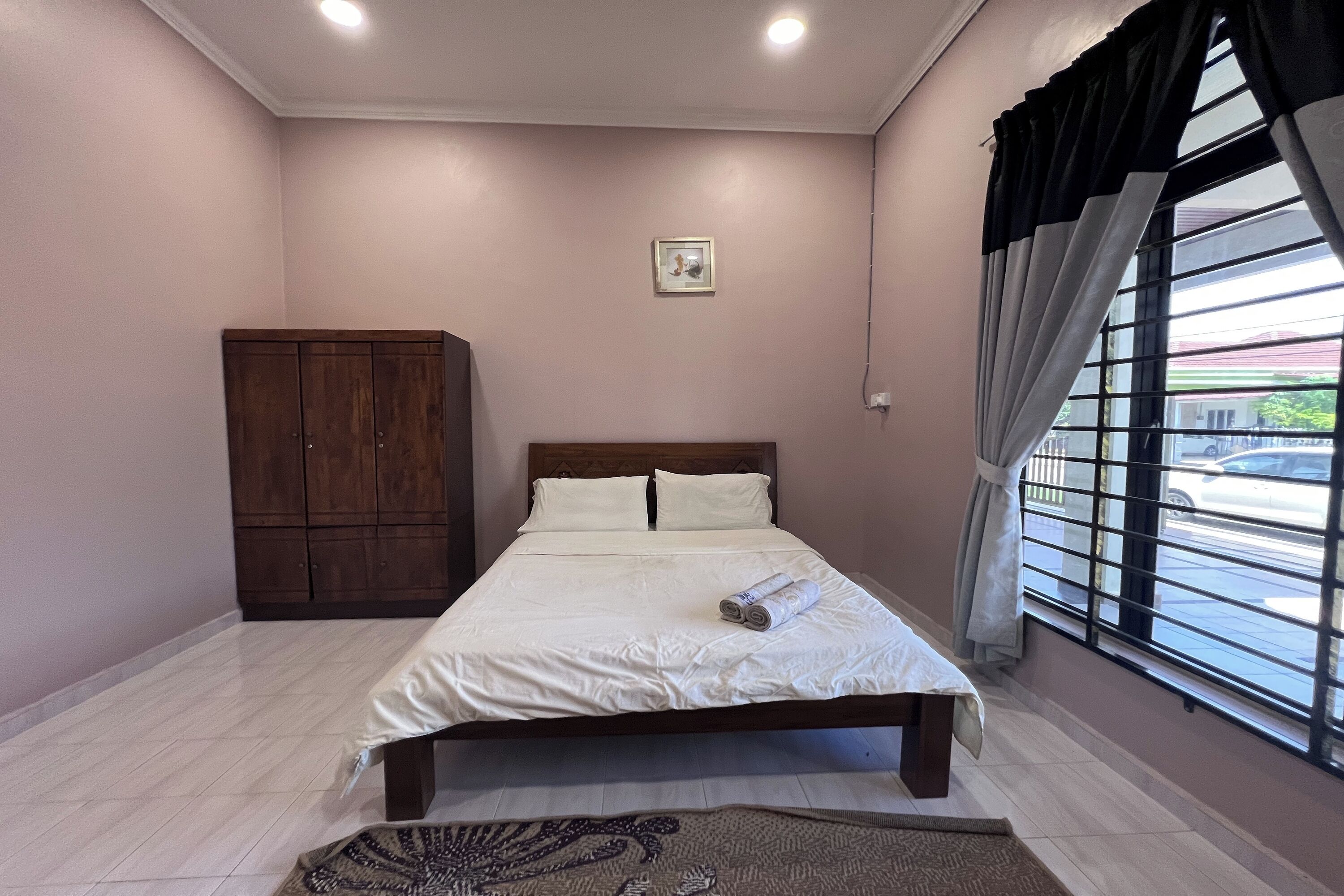 A neatly made bed with white linens, a wooden headboard, and a small picture on the wall.