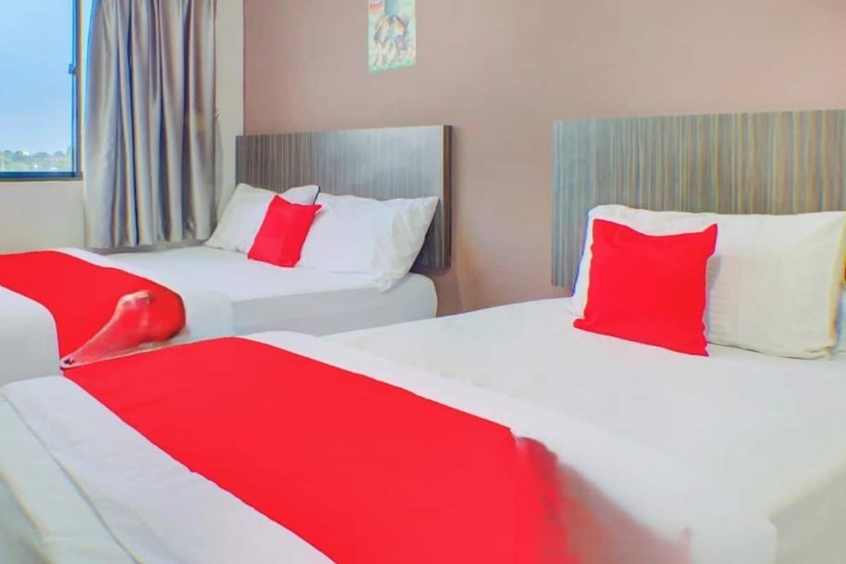 Dos camas con ropa de cama blanca y roja, un cabecero gris y una ventana con cortinas.
