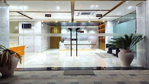 Un vestíbulo de hotel con una recepción, una planta grande en maceta y una decoración de interiores moderna.