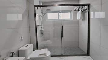 Une salle de bain moderne avec une douche à parois de verre, des toilettes et un lavabo.