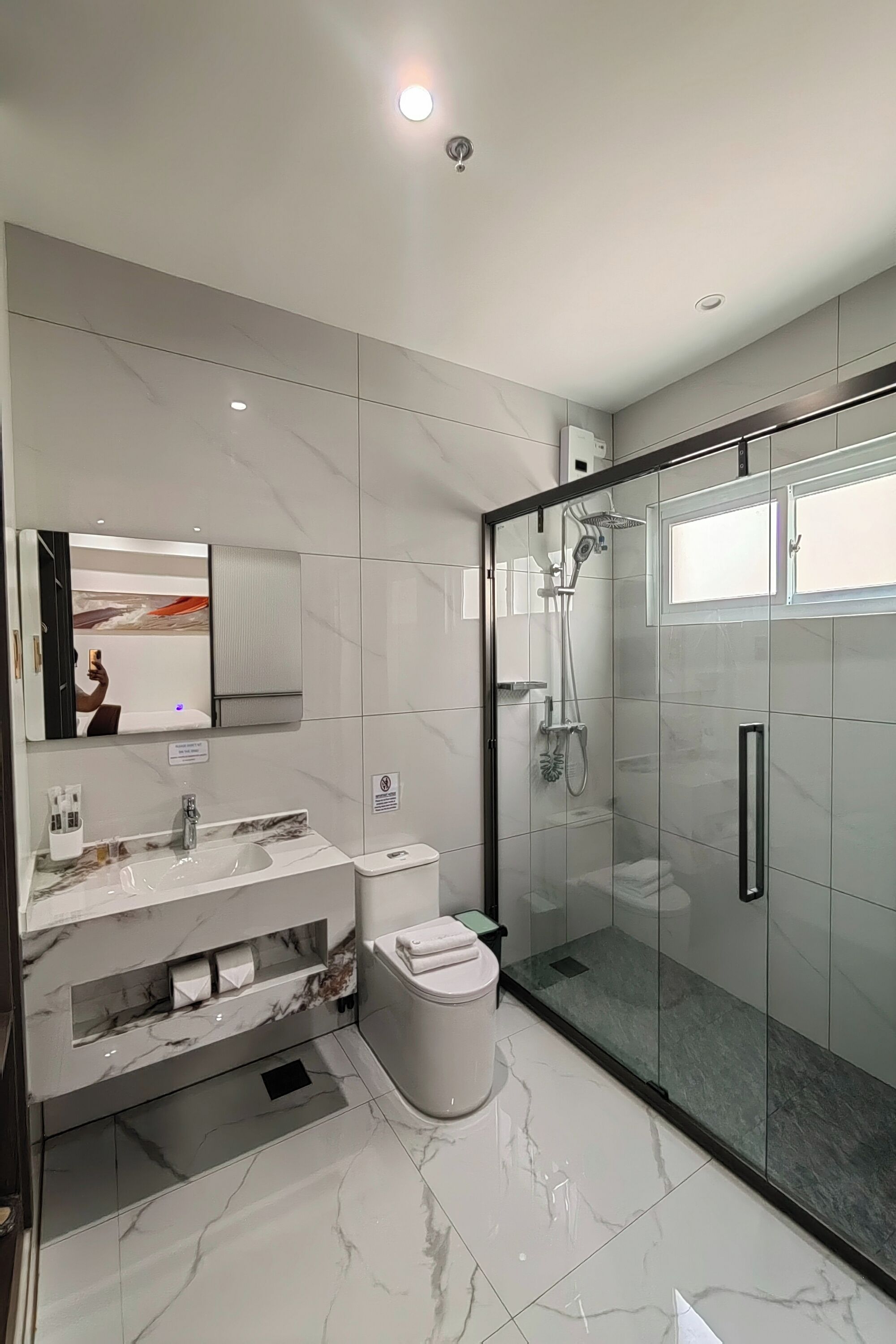 Un baño moderno con cabina de ducha de vidrio, lavamanos de mármol y un inodoro.