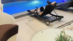 Un área de piscina interior moderna con sillones de descanso y una pared de piedra.