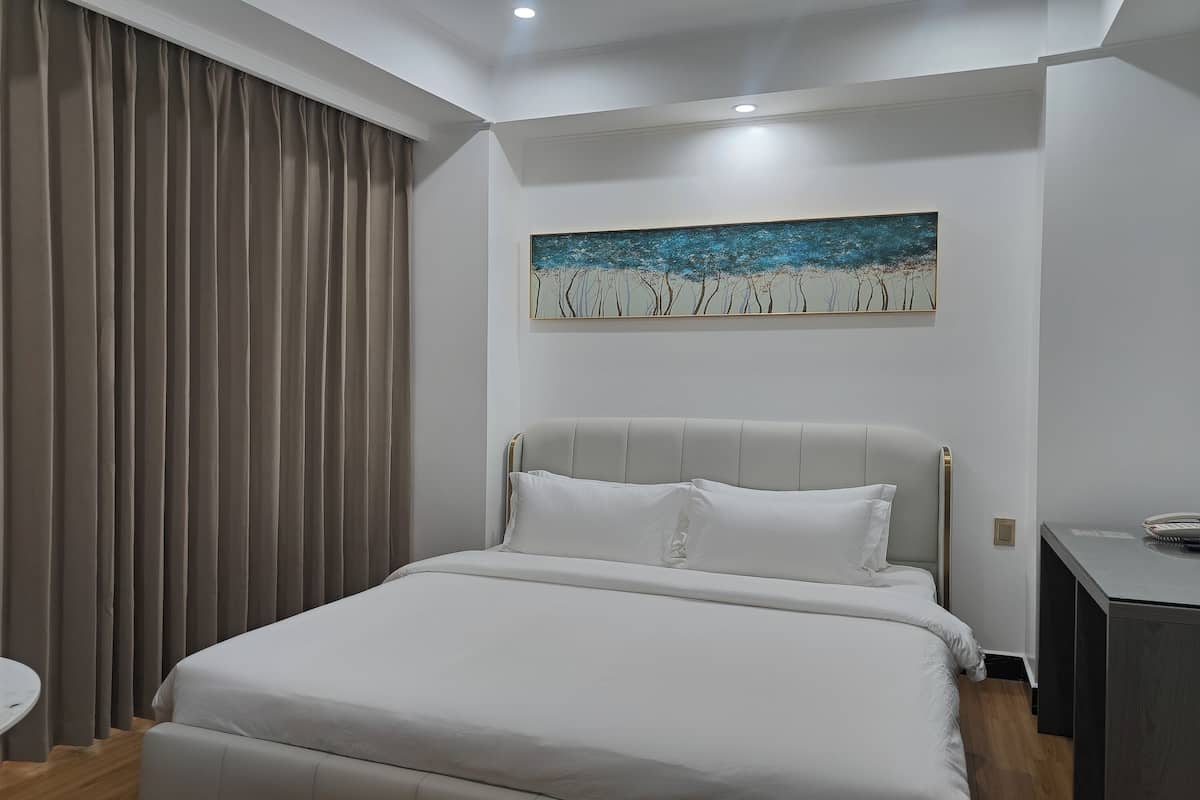 Una habitación de hotel moderna con una cama grande, un escritorio pequeño y un cuadro en la pared.