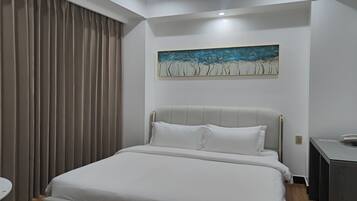 Una habitación de hotel moderna con una cama grande, un escritorio pequeño y un cuadro en la pared.