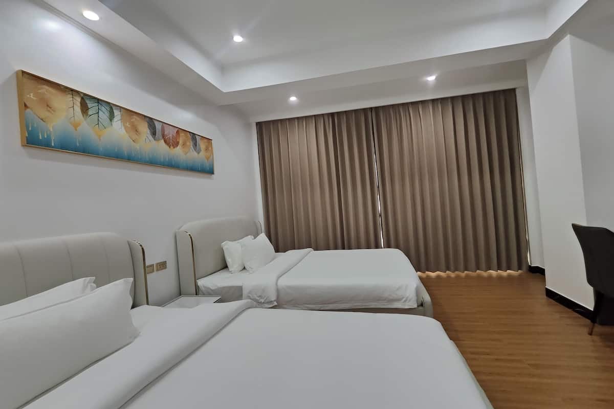 Una habitación de hotel con dos camas, un cuadro grande en la pared y una ventana con cortinas.