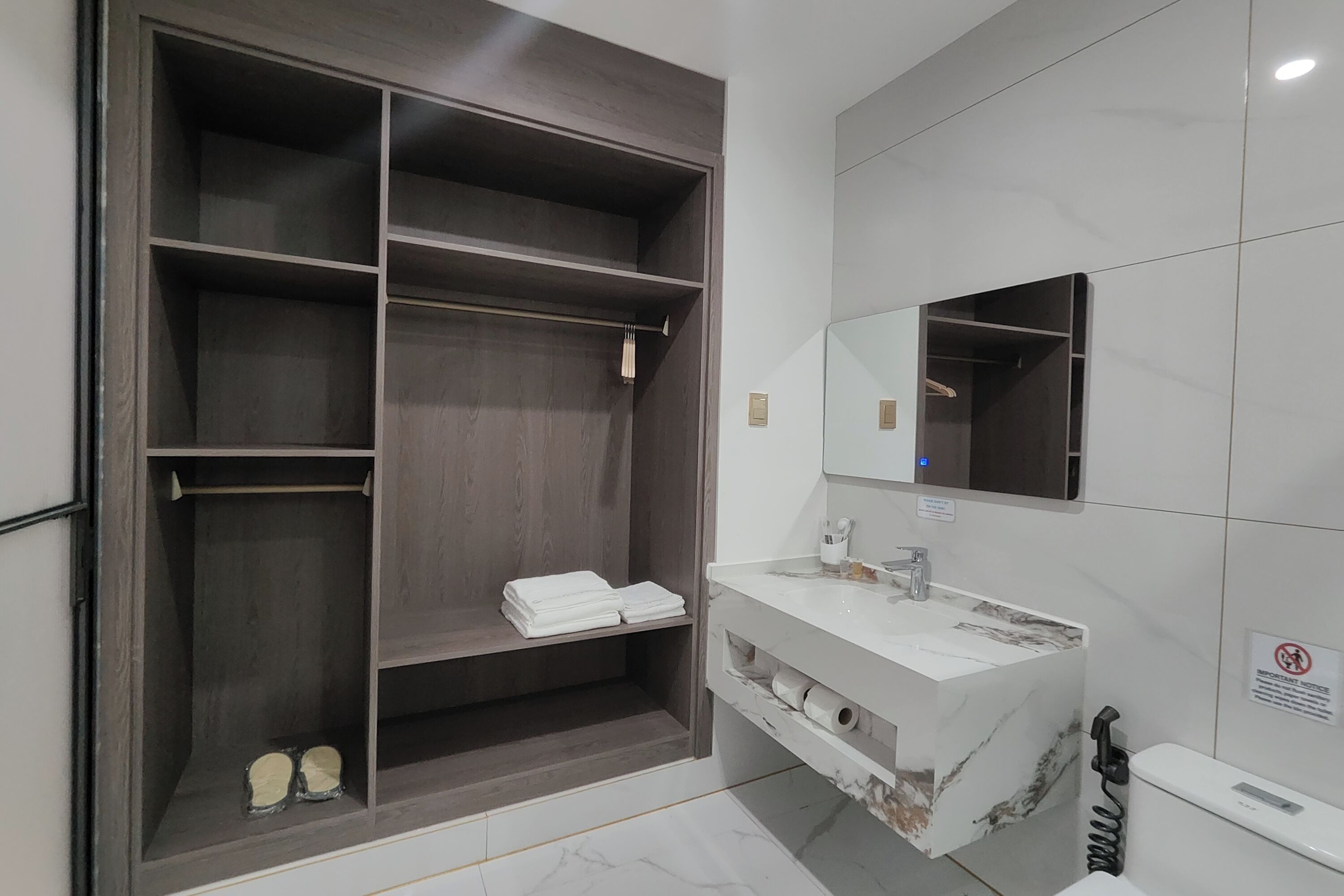 A modern bathroom with a large walk-in closet, a marble sink, and a toilet.