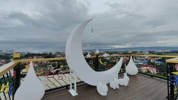 A balcony with a crescent moon decoration, star-shaped lights, and a view of a cityscape.