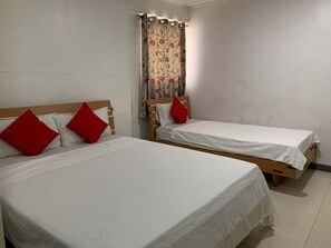 Two single beds with wooden frames and white linens, each with a red pillow. A floral curtain hangs beside one bed. - Lucky Hotel Binondo (Manila)
