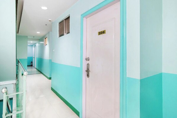 Un corridoio con pareti color acquamarina e una porta rosa contrassegnata dal numero 306.