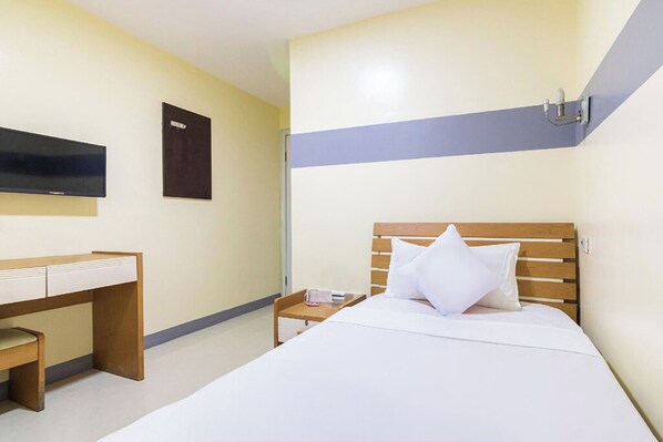 A hotel room with a bed, a desk, and a TV mounted on the wall. - Lucky Hotel Binondo (Manila)