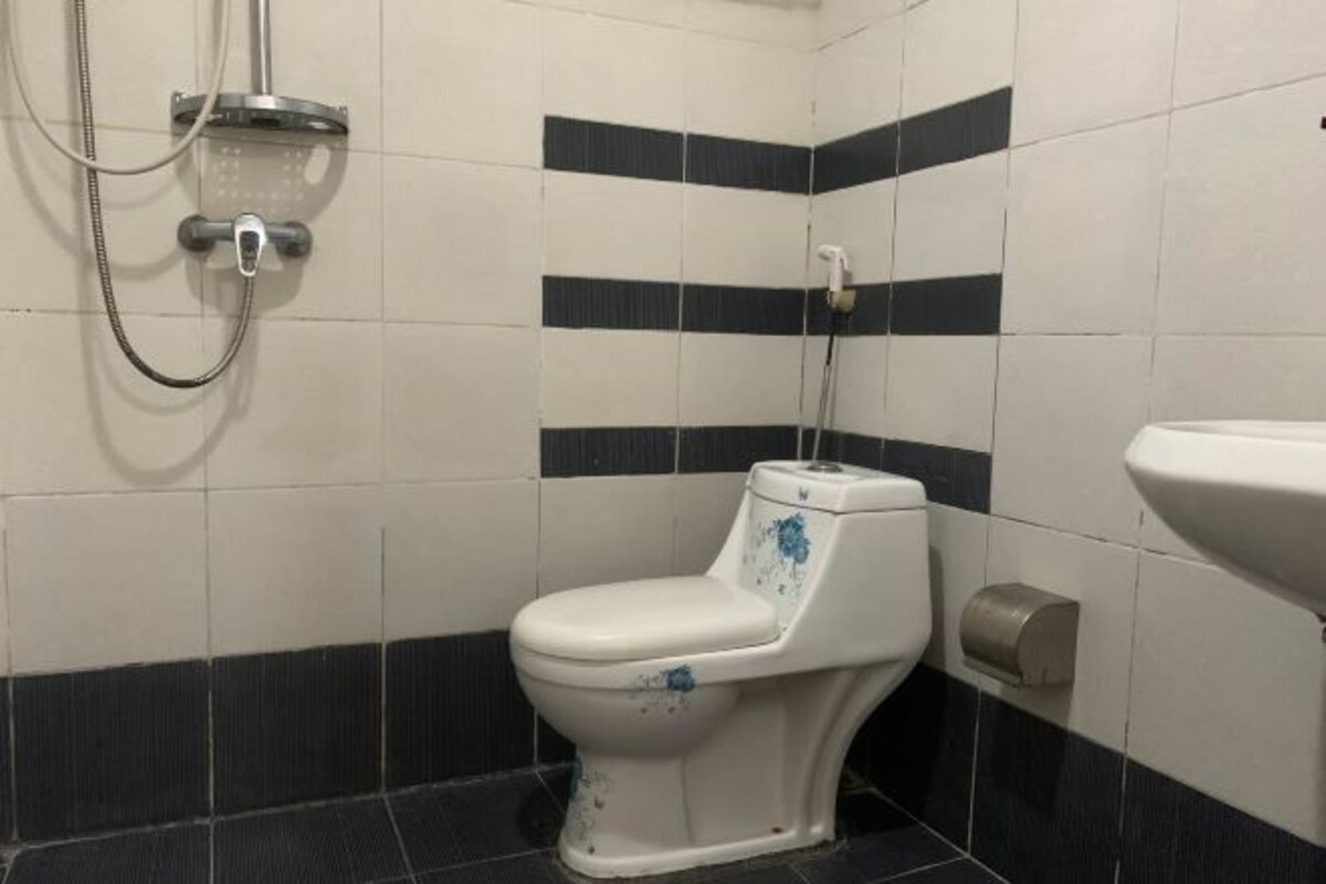 A bathroom with a white toilet, a shower, and a sink.